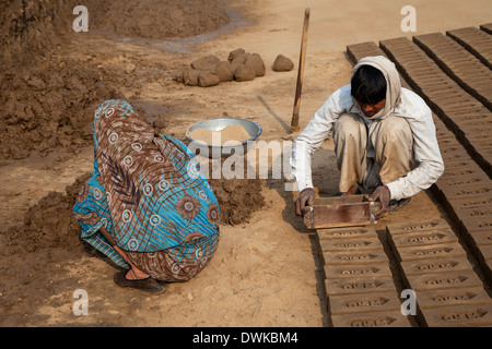 Rajasthan, India. Il marito rimuove lo stampo da mattone mentre la moglie prepara il fango per la prossima mattone. Foto Stock