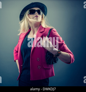 Urbano donna matura che indossa un paio di occhiali da sole e cappello, studio shot Foto Stock