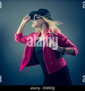 Urbano donna matura che indossa un paio di occhiali da sole e cappello, studio shot Foto Stock