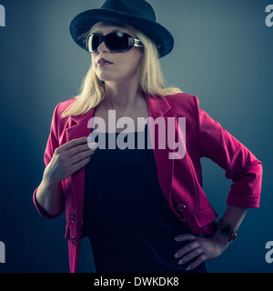 Urbano donna matura che indossa un paio di occhiali da sole e cappello, studio shot Foto Stock