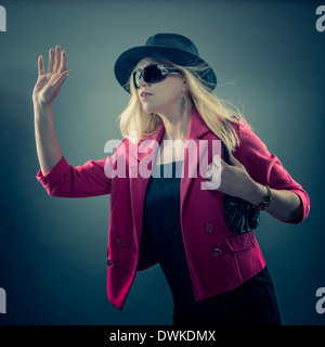Urbano donna matura che indossa un paio di occhiali da sole e cappello, studio shot Foto Stock