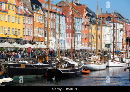 Barche ormeggiate al fianco di dipinto luminosamente edifici storici di Nyhavn a Copenaghen Foto Stock