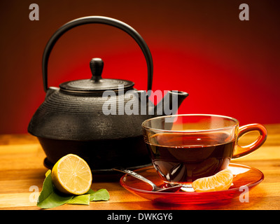 Una tazza di tè nero con teiera in background Foto Stock