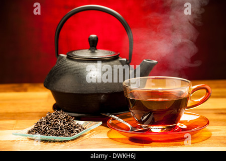 Una tazza di tè nero con teiera in background Foto Stock