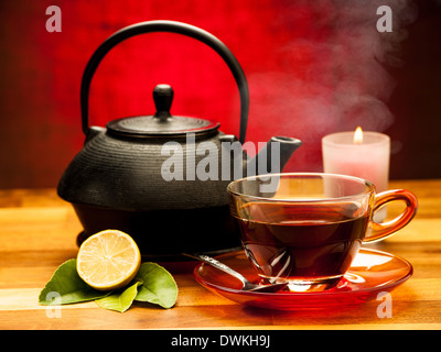 Una tazza di tè nero con teiera in background Foto Stock