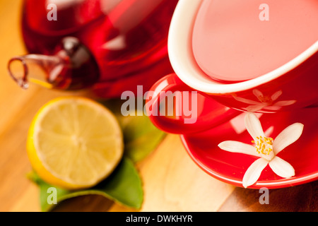 Una tazza di tè caldo con teiera in background su una scrivania in legno Foto Stock