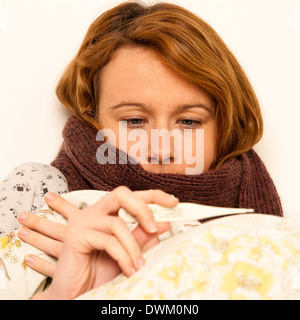 Donna controllo febbre con digital termomether ragazza con flu in appoggio a letto Foto Stock