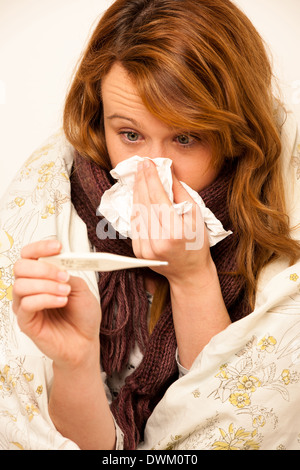 Donna controllo febbre con digital termomether ragazza con flu in appoggio a letto Foto Stock