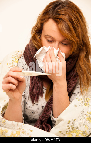 Donna controllo febbre con digital termomether ragazza con flu in appoggio a letto Foto Stock