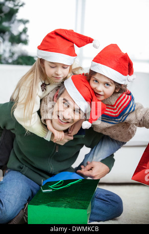 Padre Piggybacking i bambini durante il periodo di Natale Foto Stock