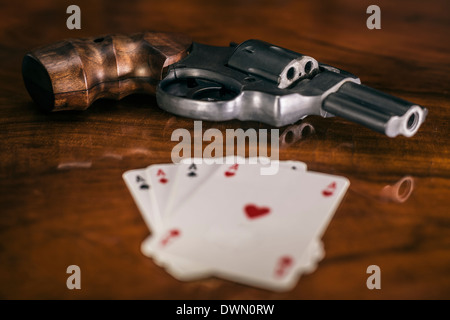 Il gioco d'azzardo rischioso concetto. Pistola e quattro assi carte sul tavolo di legno. Foto Stock