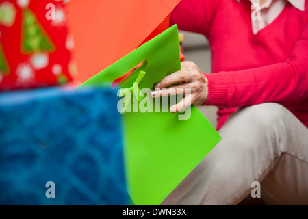 Donna senior con sacchi seduto sul pavimento Foto Stock