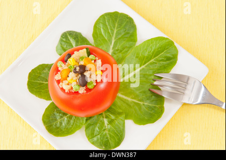 La quinoa insalata di pomodori ripieni di spinaci foglie su un giallo panno della tabella Foto Stock