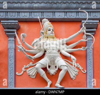 Nataraj Forma di ballo del signore Shiva con arco e frecce dio indù in arancione e bianco statua tempio sul muro esterno sollievo Foto Stock