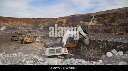 Un massiccio escavatore Liebherr minerale di carichi in un Caterpillar camion in un cielo aperto miniera di rame mentre un carrello Hitatchi attende. Foto Stock