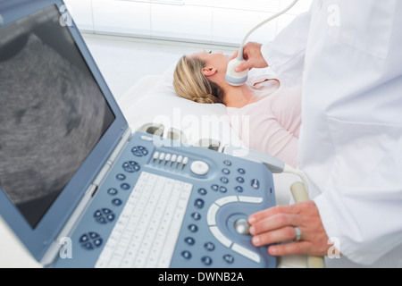 Medico di eseguire la scansione a ultrasuoni sul collo del paziente Foto Stock