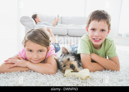 I fratelli giacente sul tappeto con Yorkshire terrier sorridente in telecamera Foto Stock