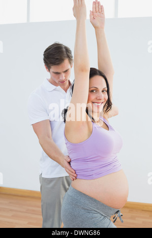 Felice donna incinta fare yoga con un personal trainer Foto Stock