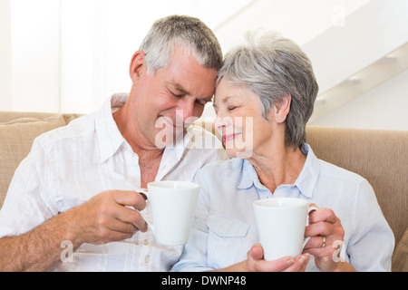 Coppia senior seduti sul divano a bere caffè toccando i capi Foto Stock