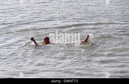 N la mattina presto nuotatore rende la maggior parte delle belle giornate di sole sulla spiaggia di Brighton questa mattina. Foto Stock