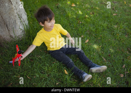 Giovane ragazzo giocando con un giocattolo aereo a park Foto Stock