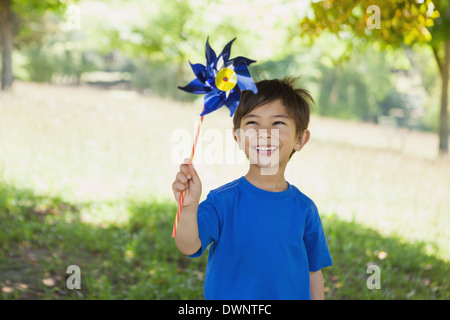 Felice carino piccolo ragazzo tenendo la girandola in posizione di parcheggio Foto Stock