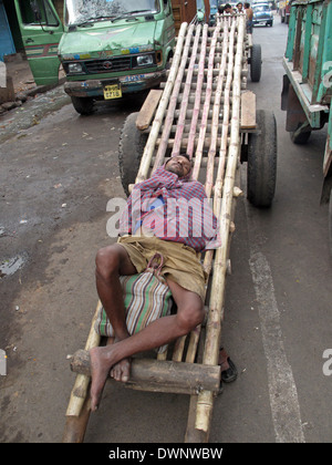 Indian uomo addormentato in attesa per i clienti per trasportare le loro merci su gennaio 25, 2009, a Kolkata. Foto Stock