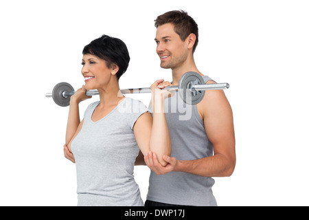 Personal trainer aiutando donna peso con barra di sollevamento Foto Stock