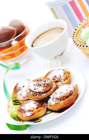 Panini alla cannella e caffè sul bianco. Pasqua. Colori di Primavera. Foto Stock