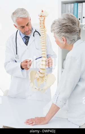 Medico di sesso maschile che spiega la colonna vertebrale del paziente senior Foto Stock