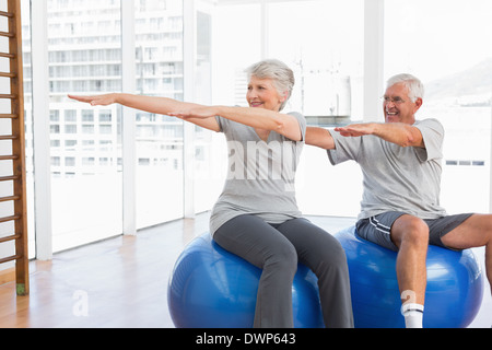 Coppia senior facendo esercizi di stretching su sfere di fitness Foto Stock