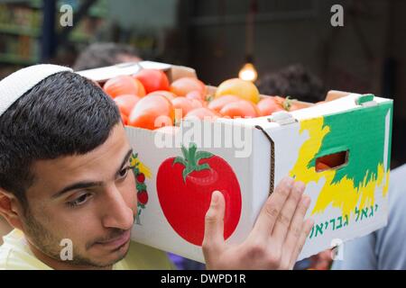 Uomo che porta cassetta con pomodori attraverso il mercato Carmel di Tel Aviv nella foto 19.2.2014 Foto Stock