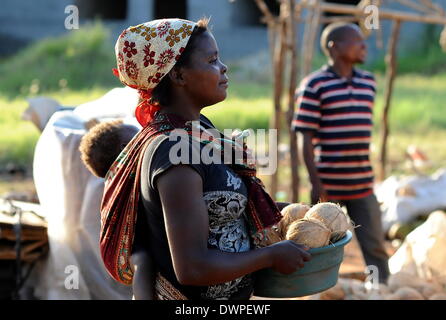 Xai-Xai, Mozambico. 02Mar, 2013. Una giovane donna che porta un bambino sulla schiena in un panno offre noci di cocco sul ciglio della strada in Xai-Xai, Mozambico, 02 marzo 2013. Foto: Britta Pedersen - NESSUN SERVIZIO DI FILO-/dpa/Alamy Live News Foto Stock