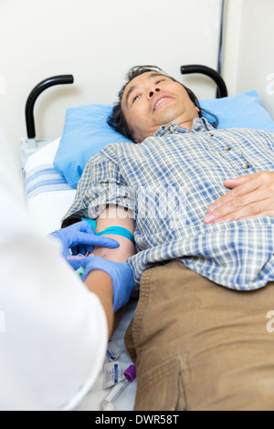 Medico il prelievo di sangue dal braccio del paziente Foto Stock