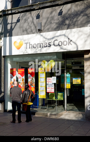 Coppia in cerca nella finestra di Thomas Cook Agenti di viaggio shop, Cardiff, Galles. Foto Stock