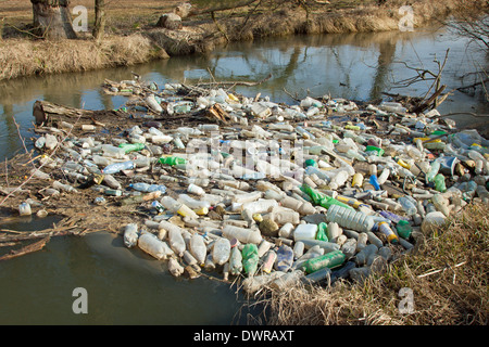 Inquinamento ambientale. Plastica, vetro e metallo Rifiuti nel fiume a inizio primavera Foto Stock