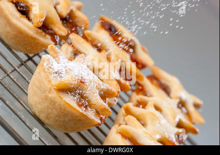 Home fatto pasticci di carne macinata essendo spolverato di zucchero a velo Foto Stock