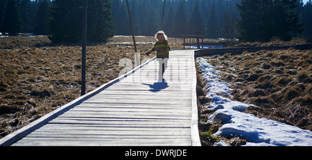 Ragazza che corre lungo la decking in legno pathway Foto Stock