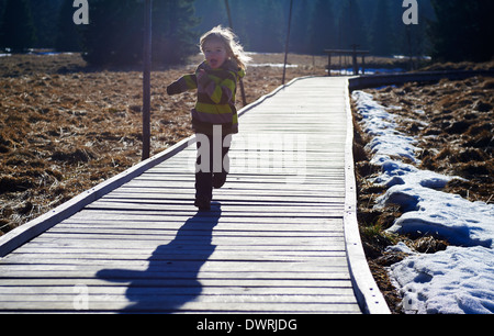 Ragazza che corre lungo la decking in legno pathway Foto Stock