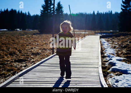 Ragazza che corre lungo la decking in legno pathway Foto Stock