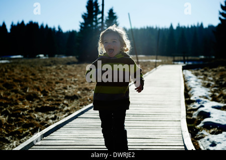 Ragazza che corre lungo la decking in legno pathway Foto Stock