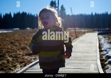 Ragazza che corre lungo la decking in legno pathway Foto Stock