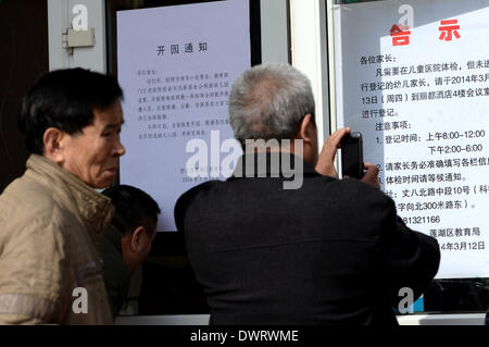 (140313) -- Xi'an, 13 marzo 2014 (Xinhua) -- genitori guardare attraverso bandi di gara al di fuori del Fengyun Lanwan Kindergarten, che è stato chiuso per dare ai bambini di farmaci antivirali, a Xi'an, capitale della Cina nord-occidentale della provincia di Shaanxi, 13 marzo 2014. Il Fengyun Lanwan Kindergarten e Hongji Xincheng Kindergarten qui sono state chiuse il 11 marzo dopo i genitori divulgato la scuola è stata per lungo tempo la somministrazione di farmaci antivirali per bambini. La polizia ha messo il asili privati' rappresentante legale, principale e kindergarten medico nella custodia. Alcuni genitori dice Xinhua i loro bambini sono state vivendo discomfo Foto Stock