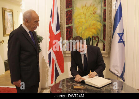 Gerusalemme, Israele. Xii Mar, 2014. La visita del Primo Ministro britannico David Cameron (R) Firma il libro degli ospiti mentre il presidente israeliano Shimon Peres in piedi vicino al Presidente israeliano ha la residenza in Gerusalemme, il 12 marzo 2014. Primo Ministro britannico David Cameron Mercoledì ha invitato la Knesset (parlamento) a raggiungere per la storica pace con i palestinesi, durante la sua prima visita in Israele come primo ministro. Credito: piscina/Dan Balitly/Xinhua/Alamy Live News Foto Stock