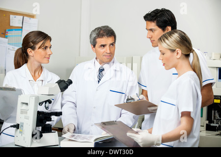 Scienziato con gli studenti a prendere appunti in laboratorio Foto Stock