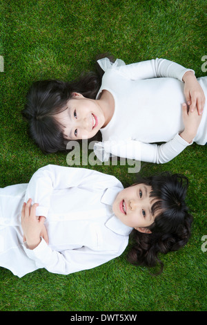 Due ragazze sdraiati sull'erba Foto Stock