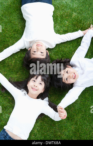 Tre bambini sdraiati sull'erba Foto Stock