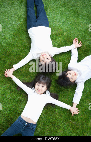 Tre bambini sdraiati sull'erba Foto Stock