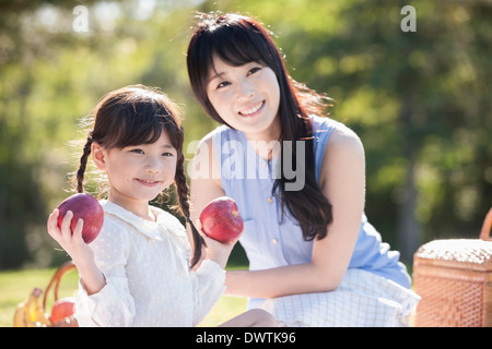 Una madre e una figlia mangiare frutta nella natura Foto Stock