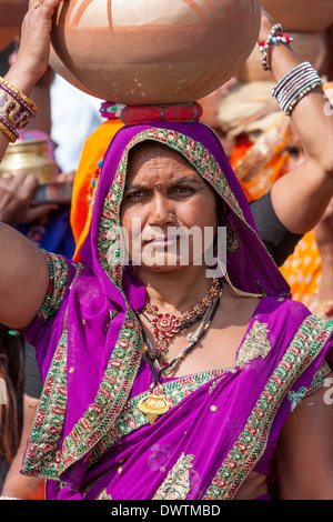 Abnaheri, Rajasthan, India. Donna che trasportano pentole sul suo capo come lei partecipa a un pre-la celebrazione dei matrimoni. Foto Stock